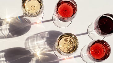 Red, rose and white wine top view in sunlight. Assorted wine in glass. Dark shadows.