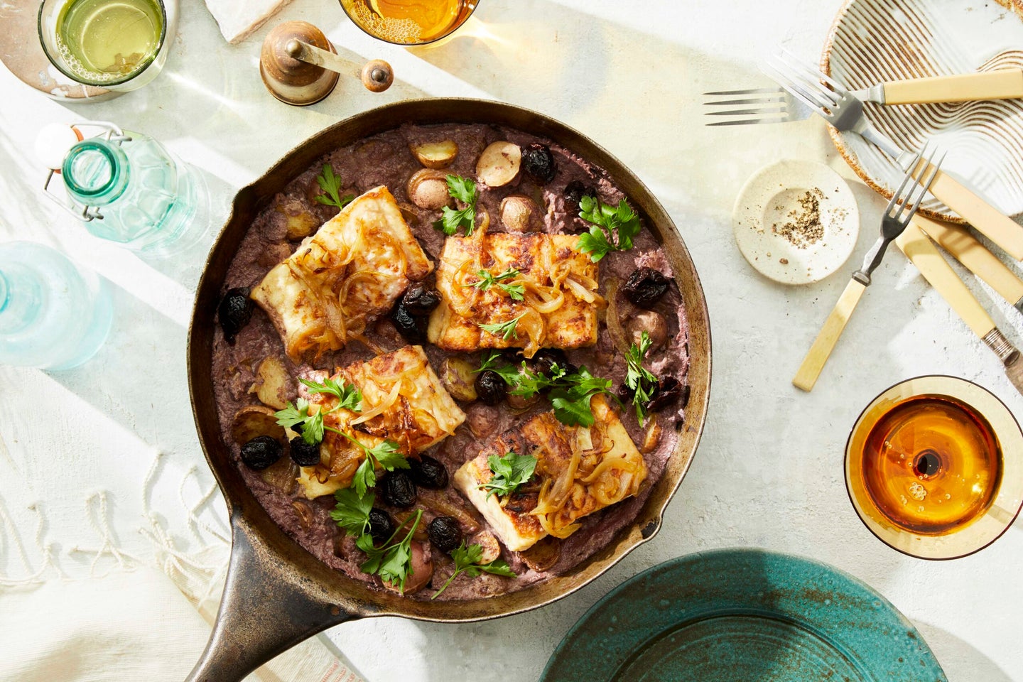 skillet of salt cod on a bed of port-wine onions and potatoes