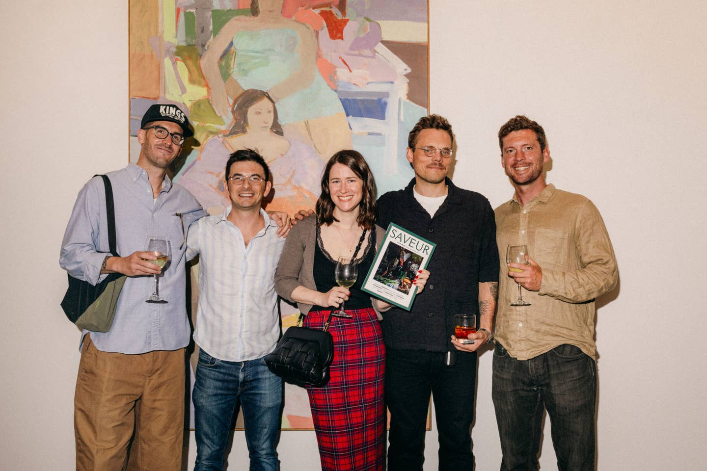 Penki žurnalo redaktoriai, stovintys priešais didelį, spalvingą paveikslą Hollis Taggart galerijoje.